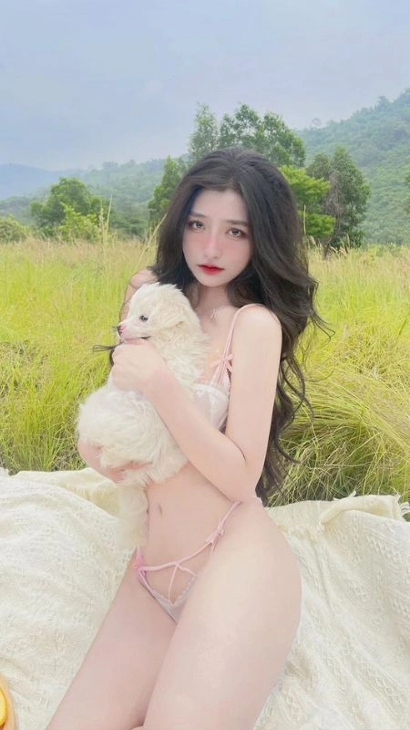 Cô nàng gợi cảm trong bộ bikini hồng nhạt, ôm cún con giữa đồng cỏ lãng mạn